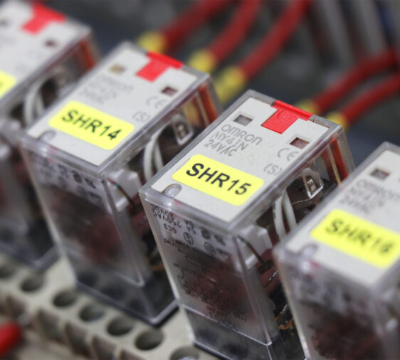 Componenten in een besturingskast, elk voorzien van gele componentlabels voor eenvoudige codering