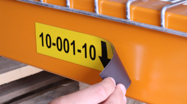 Close-up van een hand die een magnetisch magazijnlabel van een stelling verwijdert
