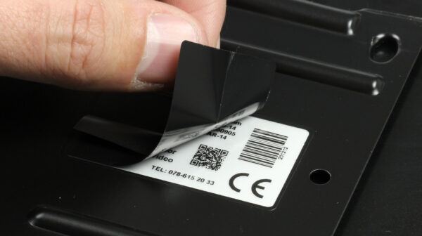 Close-up van een hand die het beschermlaminaat van een PaintLabel verwijdert na poedercoaten