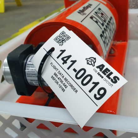Industriële tag met identificatiegegevens zoals een QR-code bevestigd aan een zwarte doos voor gebruik in een vliegtuig