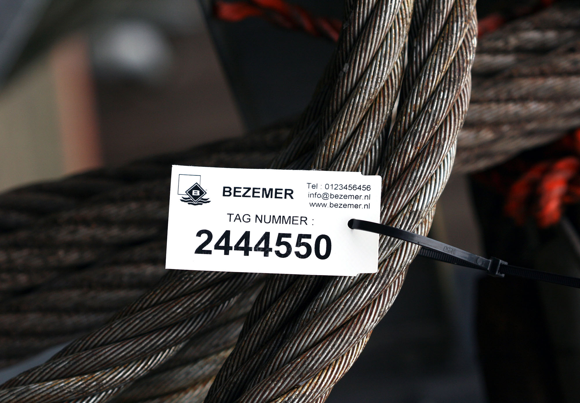 Onscheurbare witte industriële tag bevestigd aan een staalkabel voor duidelijke identificatie